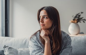 Close up of sad pensive millennial woman sit alone thinking about relationships personal problems, upset thoughtful young female lost in thoughts feel lonely depressed pondering or mourning at home